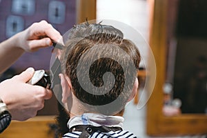 Barbers hands making haircut to man using trimmer photo