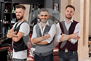 Barbers wearing white shirts showing posing with crossed hands.