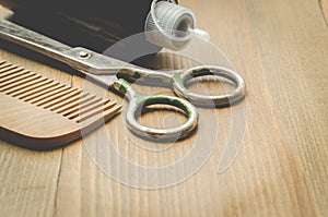 Barbershop concept. Hairbrushes, sprayer and a scissors on a wooden board, selective focus and copy space