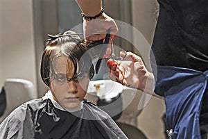 barbershop cuts the ends of wet clean hair to a boy