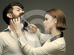 Barbershop or hairdresser concept. Woman hairdresser cuts beard with scissors. Guy with modern hairstyle visiting