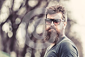 Barbershop and style concept. Man with beard and mustache on strict face, nature background, defocused. Bearded man