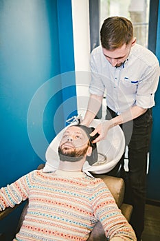 Barbershop theme. Hairdresser for washing hair in a barbershop. Hands male hairdresser close-up washes hair with foam and shampoo