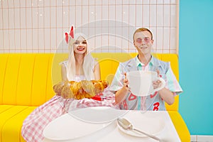 barbie girl and boyfriend ken in cafe with a big cup of coffee and a croissant