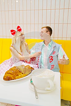barbie girl and boyfriend ken in cafe with a big cup of coffee and a croissant