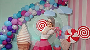 Barbie girl with shoes in hand near huge sweets.