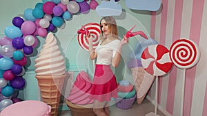 Barbie girl with shoes in hand near huge sweets.