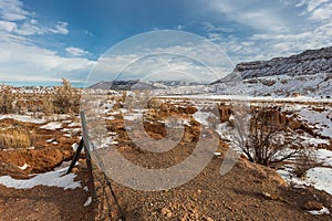 Barbwire fence in front of red rock field and large mesa plateau in rural New Mexico