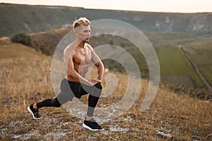 Bare-chested man lunging in nature