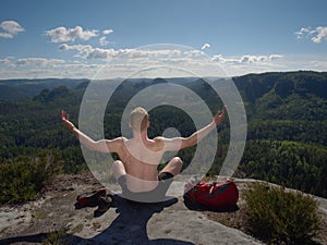 Bare-chested man sit on peak over mountains. Shirtless man