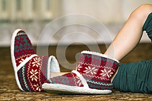 Bare child legs and feet in red winter christmas boots with ornament pattern