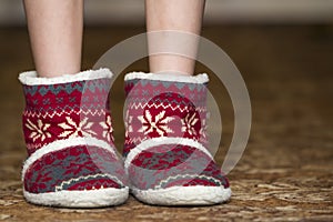 Bare child legs and feet in red winter christmas boots with ornament pattern