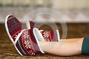 Bare child legs and feet in red winter christmas boots with ornament pattern