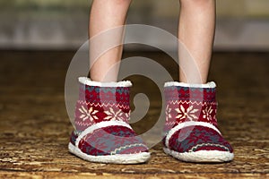 Bare child legs and feet in red winter christmas boots with ornament pattern