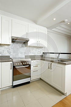 Bare, clean kitchen with an oven, white drawers and cabinets