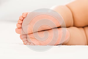 Bare feet of a baby sleeping on a white blanket