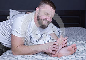 Bare feet of a child. Dad tickles his child\'s feet sticking out from under the blanket. Laughter and joy of father