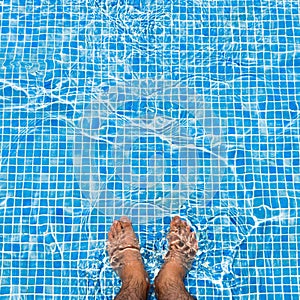 Bare feet cooling off in the pool relaxing concept squ