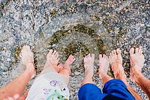 Bare feet of a family cooled in the water of a stream, connecting with nature, far from everything