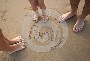 bare feet of family, father, mother and child on sandy beach. The inscription Family on the sand