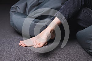 Bare feet of a girl. A girl in jeans with bare feet. Foot and heel