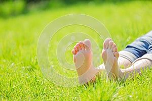 Bare feet on green grass with autumn leaves