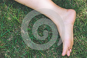 Bare feet and hands with creative teens manicure and pedicure on the green grass lawn background,