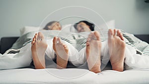 Bare feet male and female moving in bed under blanket in funny dance