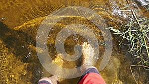 Bare feet of a man go into the water of a river. Slow Motion