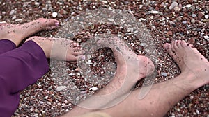 Bare feet of a man and a woman lying side by side on a pebble beach