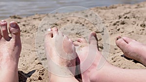 Bare Feet of Mother and Child in the Sand Lies on a Sandy Beach near the Ocean