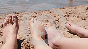 Bare Feet of Mother and Child in the Sand Lies on a Sandy Beach near the Ocean