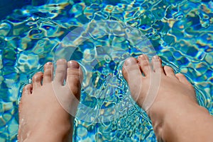 Bare feet resting on the surface of pool water