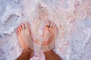 Bare feet on the salt of a dried lake. Spa or travel concept.