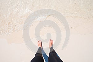 Bare feet stand on white beach