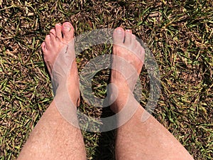 Bare feet stepping on the grass and dirt floor