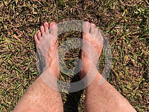 Bare feet stepping on the grass and dirt floor