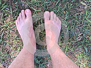 Bare feet stepping on the grass and dirt floor