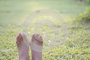 Bare feet of woman lie on green grass for relaxing , copy space
