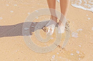 Bare feet of a young girl in the sand on the beach of the sea coast