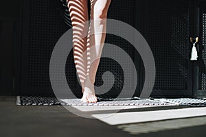 Bare feet of young woman in the bathroom at home, light and shadow