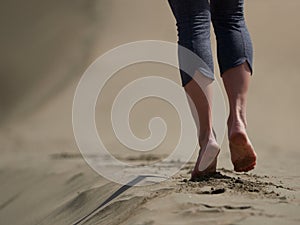 Bare feet of young woman jogging/walking on the beach