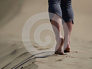 Bare feet of young woman jogging/walking on the beach at sunrise