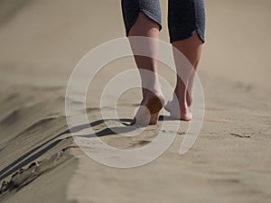 Bare feet of young woman jogging/walking on the beach at sunrise