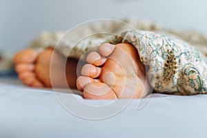 Bare feet young woman under blanket