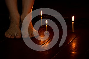 bare female feet on the floor at home in the dark near candles, female feet photo