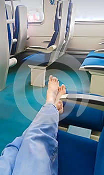 Bare female feet on a seat in an empty train car