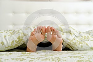 Bare female feet sticking out from under the blanket