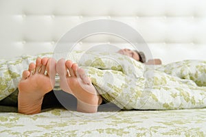 Bare female feet sticking out from under the blanket