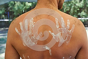 Bare man back hand marked sunscreen